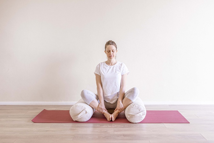 A young pregnant woman practices Bound Angle Pose to soothe symptoms of acid reflux.