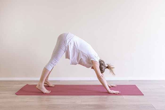 A young mom comes into downward facing dog yoga pose for pregnancy back pain.