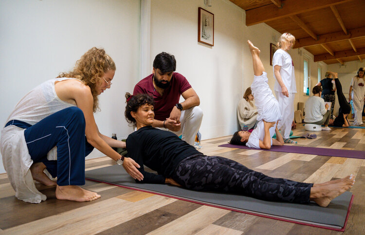 A yoga teacher trainer demonstrates proper adjustment techniques to a UK yoga student on a 200-hour yoga teacher training course at Arhanta Yoga Ashrams