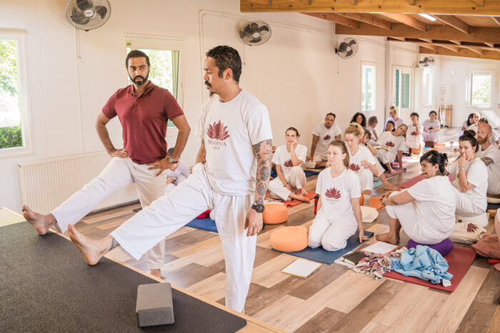 Yoga teacher and student perform a demonstration in front of a class Yoga teacher and student perform a demonstration in front of a class