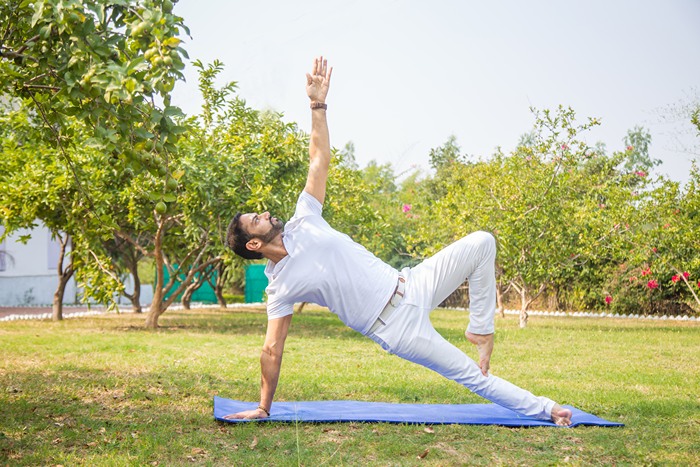 Yoga teacher observing alignment while practicing variation of Triangle Pose