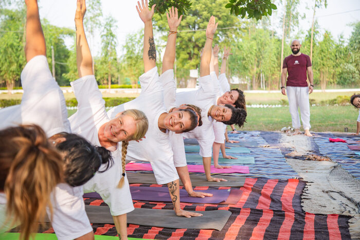 Hatha yoga teacher training practitioners performing side plank under the teacher’s guidance.