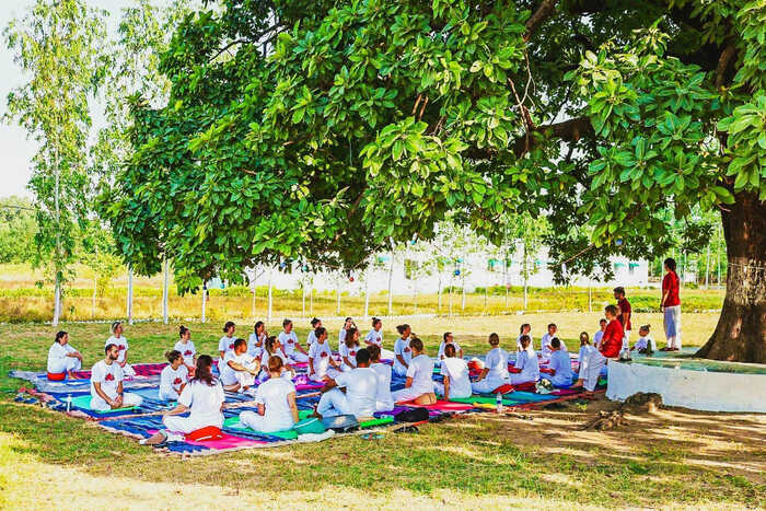 Yoga students learning philosophy under a tree in Indian ashram setting