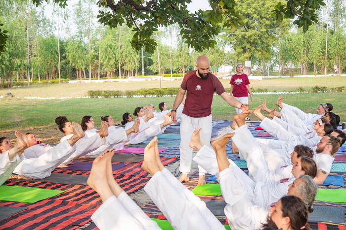 New yoga teacher guiding students in boat pose, also known as Navasana